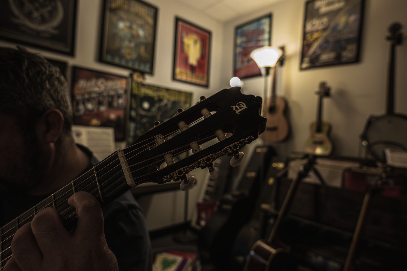 Close-up of hands on the neck of a classical guitar in the warm lamplight of the studio